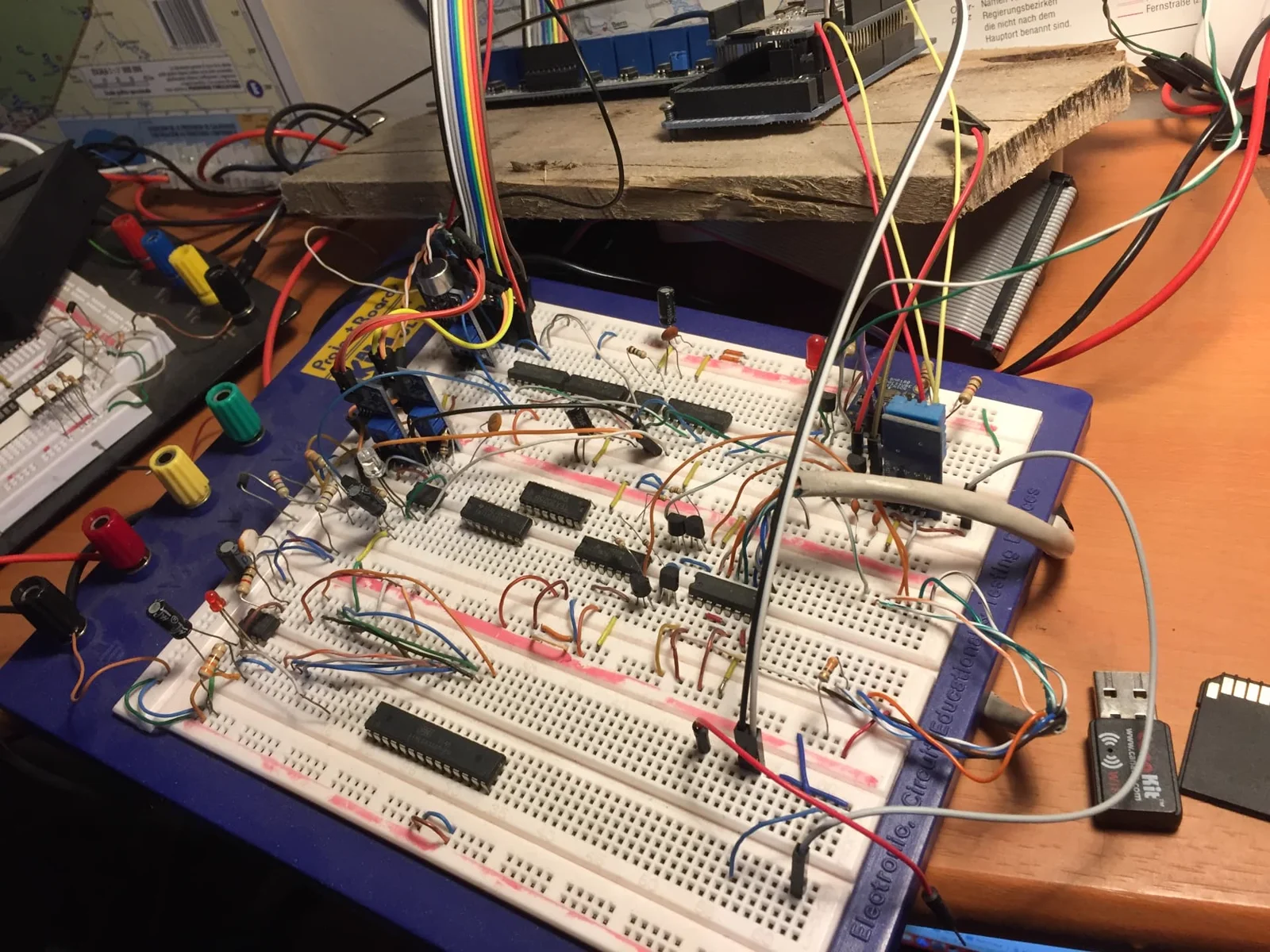 Dense breadboard build with several integrated circuits, relays and ribbon cables on a workbench