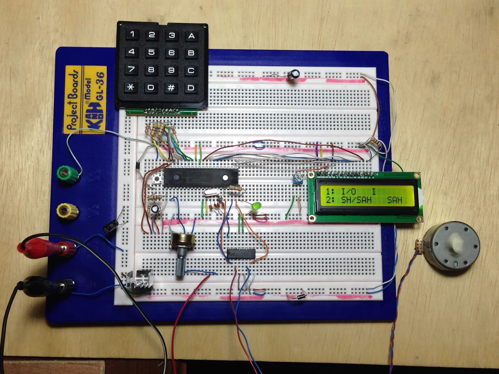 Breadboard prototype with a microcontroller, matrix keypad, character LCD showing menu options and a small DC motor