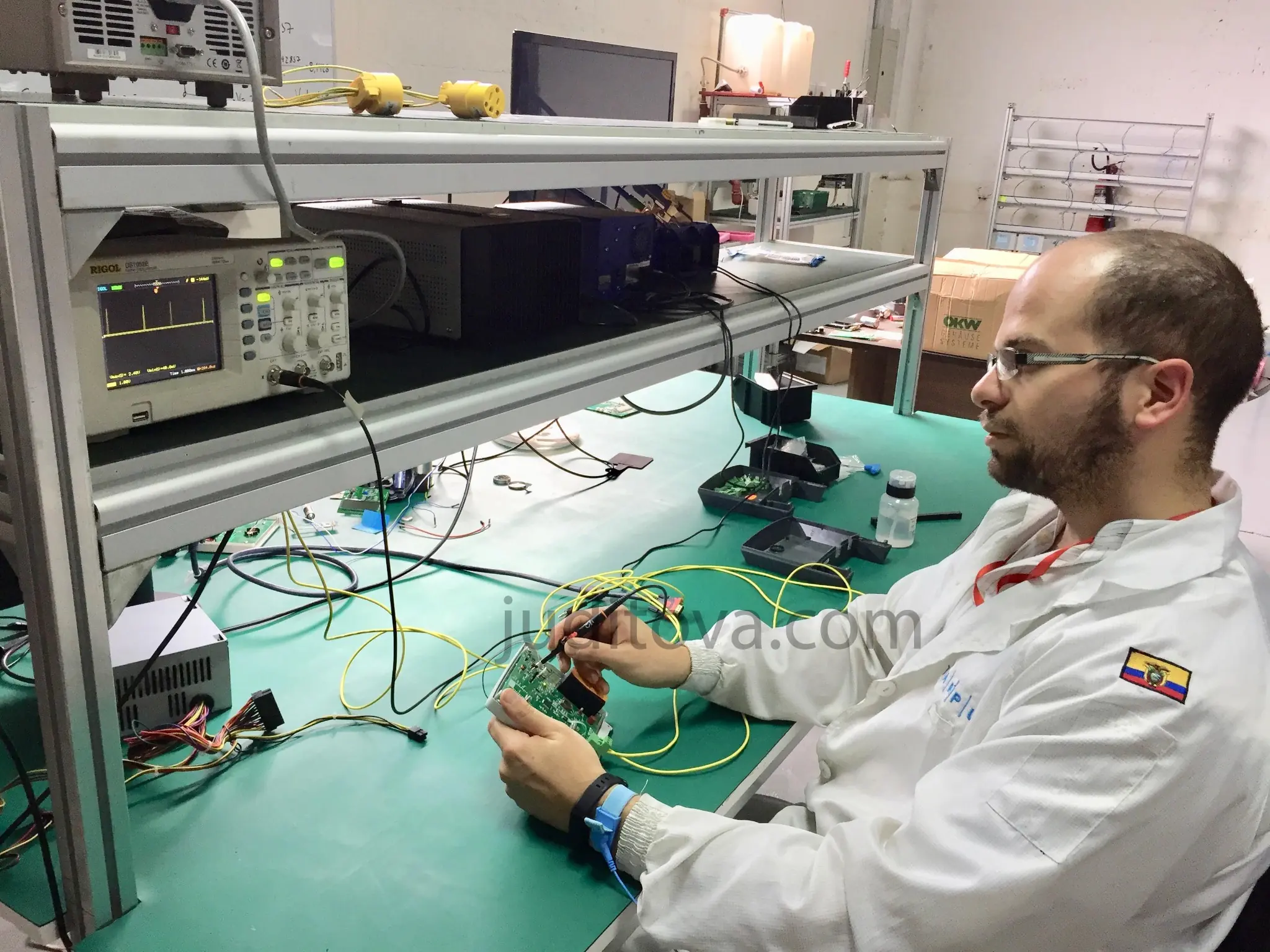 Working at an electronics bench with an oscilloscope, power supply and a circuit board under test
