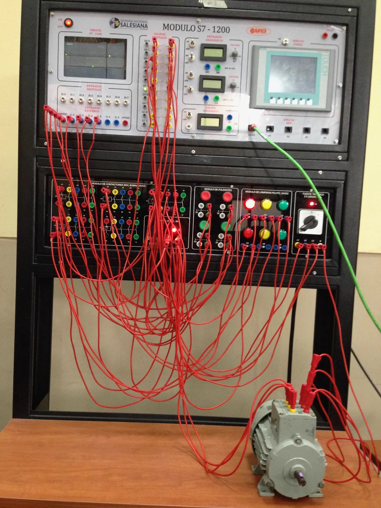 Siemens SIMATIC S7-1200 PLC training module wired with red patch cables to contactors, pushbuttons and a three-phase motor