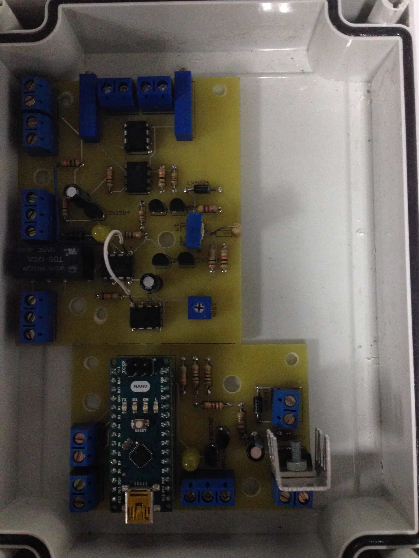 Two finished control boards with an Arduino Nano, relay and screw terminals mounted inside a sealed enclosure