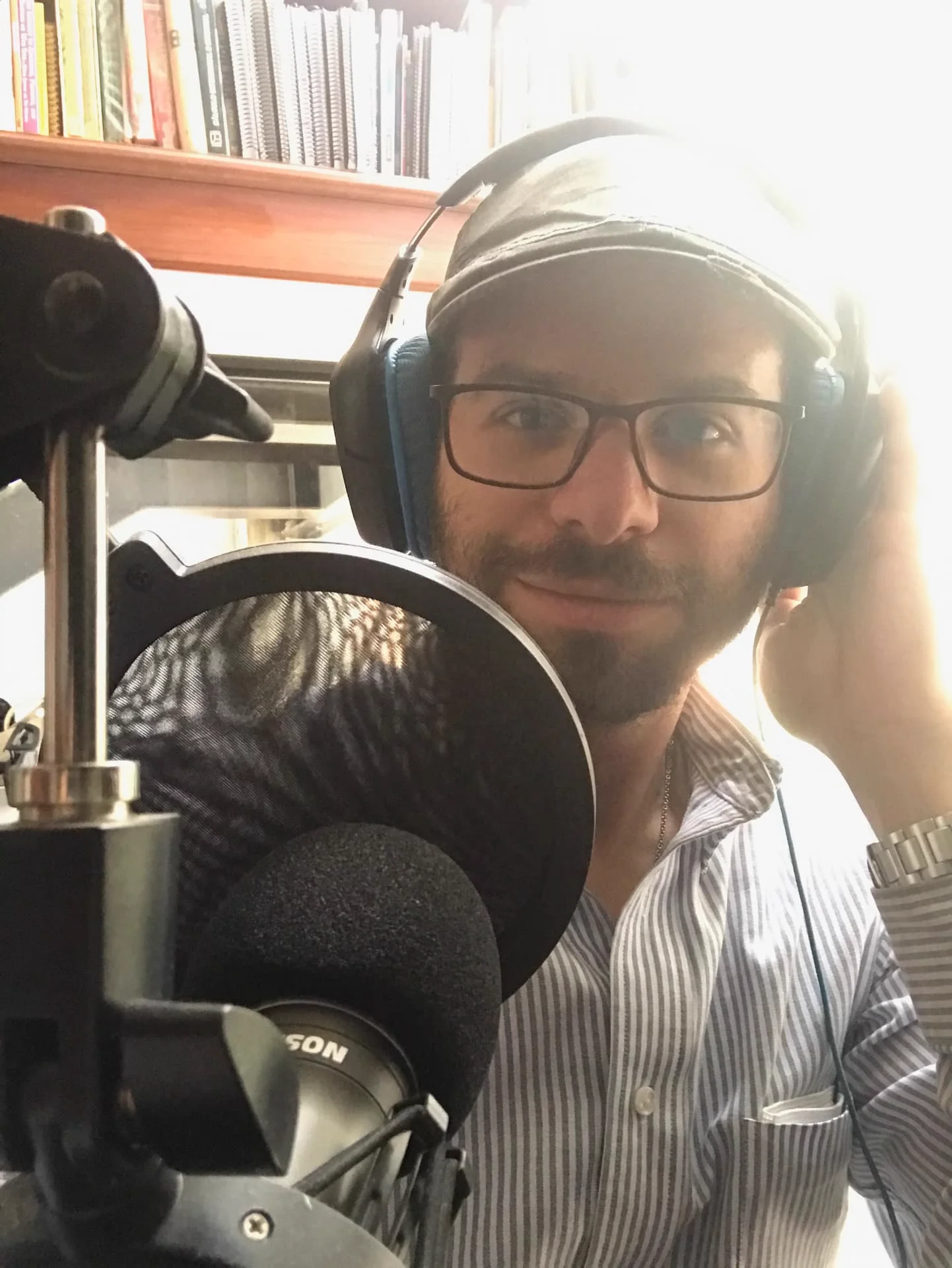 Juditova wearing headphones next to a studio microphone and pop filter while recording an episode