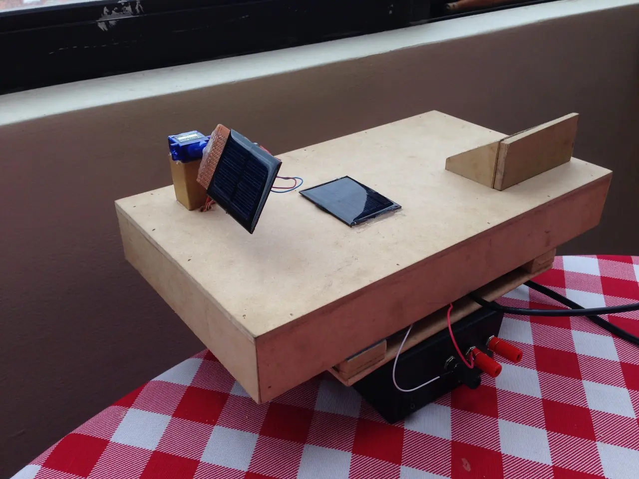 Wooden prototype platform with a small solar panel, servo motor and battery box built during laboratory work